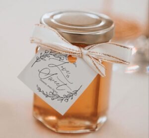 Marturie pentru nunta sau botez, un borcan mic de sticla plin cu miere de albine, decoratu cu o eticheta alba si funda - un cadou dulce si natural de la Gifts-Heaven.